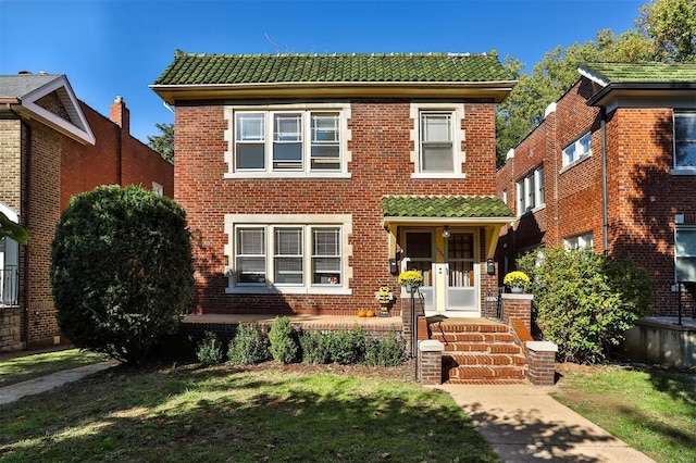 view of front of home featuring brick siding, covered porch, and a tile roof