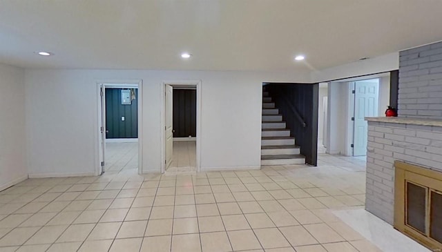 basement featuring light tile patterned flooring and a brick fireplace