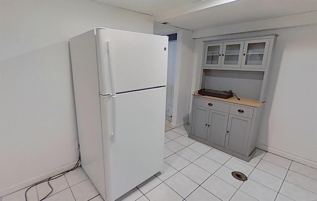 kitchen with white refrigerator, light tile patterned floors, and gray cabinetry