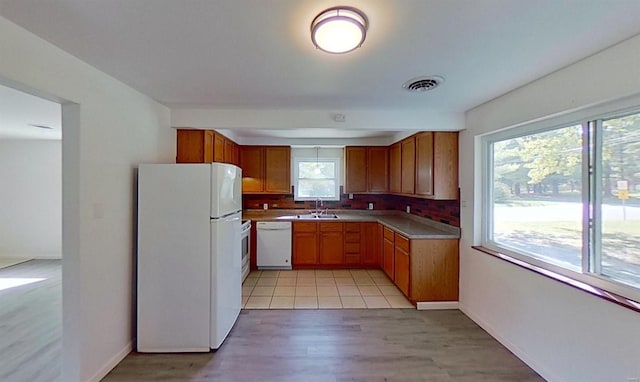 kitchen featuring tasteful backsplash, white appliances, sink, and light wood-type flooring