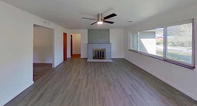 unfurnished living room featuring a fireplace, dark hardwood / wood-style floors, and ceiling fan