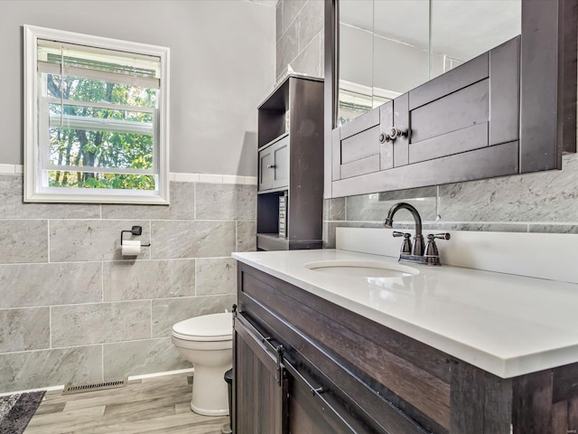 bathroom with tile walls, hardwood / wood-style flooring, vanity, and toilet