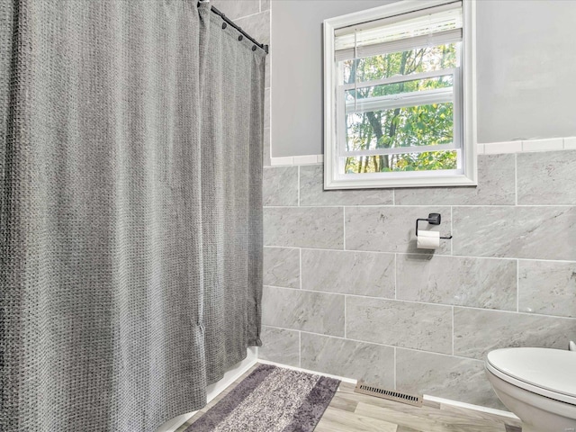 bathroom with walk in shower, hardwood / wood-style floors, tile walls, and toilet