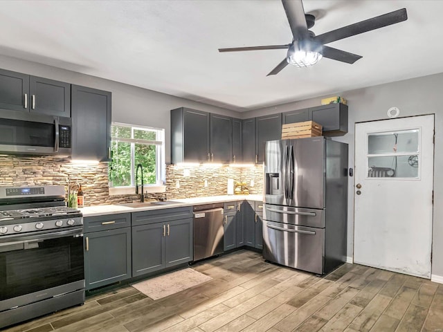 kitchen featuring stainless steel appliances, wood-type flooring, backsplash, and sink