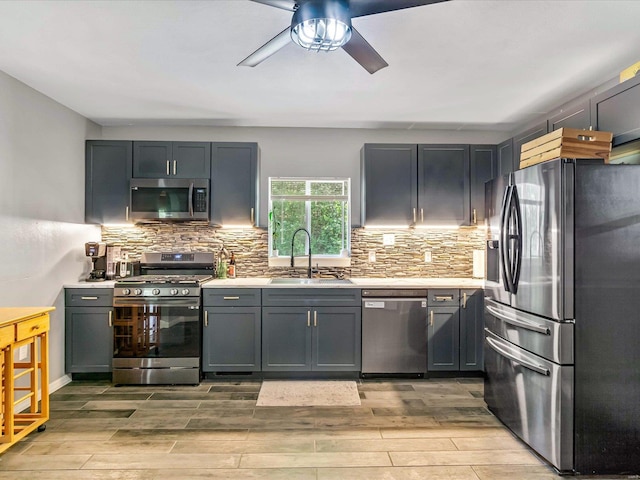 kitchen with ceiling fan, stainless steel appliances, gray cabinetry, sink, and light hardwood / wood-style flooring