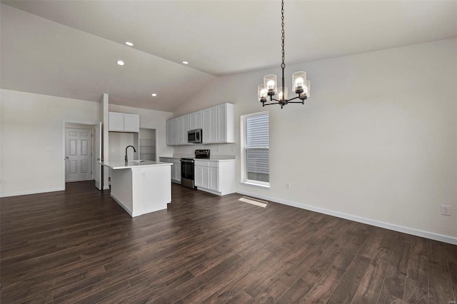 kitchen with dark hardwood / wood-style flooring, decorative light fixtures, vaulted ceiling, stainless steel appliances, and an island with sink