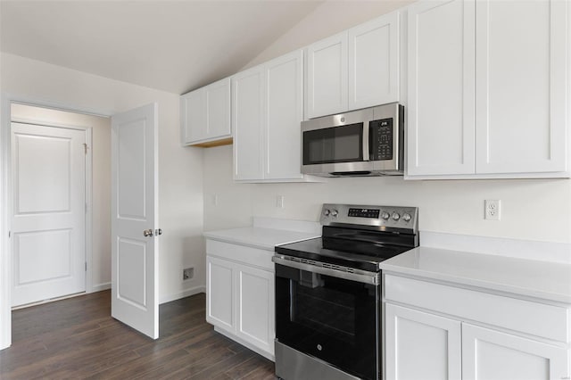 kitchen with lofted ceiling, dark hardwood / wood-style floors, appliances with stainless steel finishes, and white cabinetry