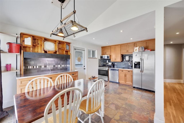 kitchen with sink, vaulted ceiling, appliances with stainless steel finishes, decorative light fixtures, and backsplash