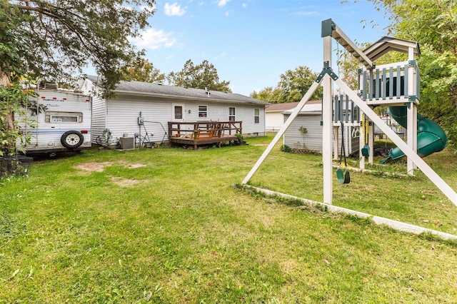 rear view of property featuring a yard, a deck, a playground, and central AC unit