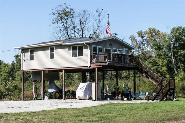 back of house featuring a wooden deck, a yard, and a carport