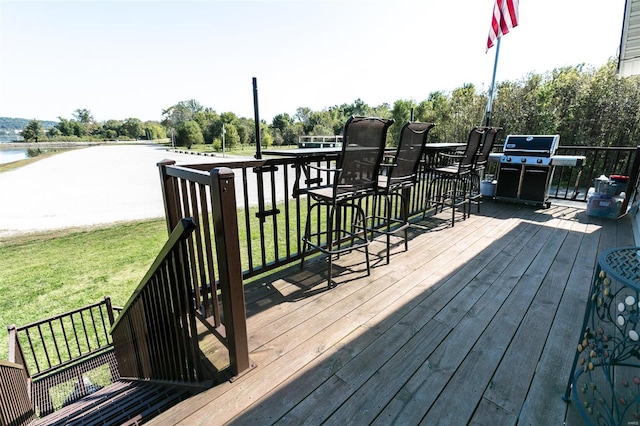 wooden terrace with a water view, a grill, and a yard