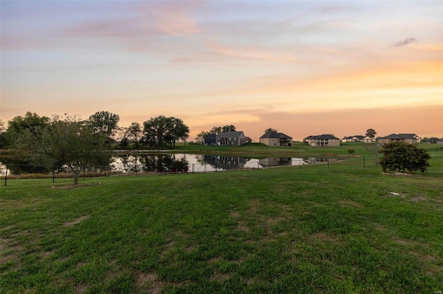 yard at dusk featuring a water view