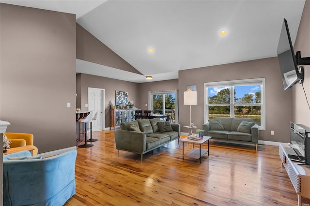 living room with light wood-type flooring and high vaulted ceiling