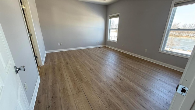 spare room with baseboards and wood finished floors