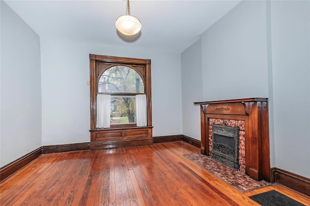 unfurnished living room with wood-type flooring and a tiled fireplace