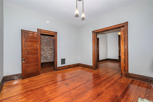 unfurnished room with wood-type flooring and an inviting chandelier