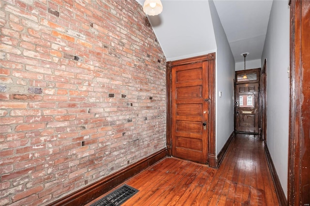 corridor featuring dark wood-type flooring and brick wall