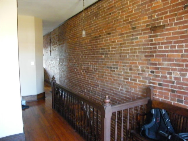 corridor featuring dark hardwood / wood-style floors and brick wall