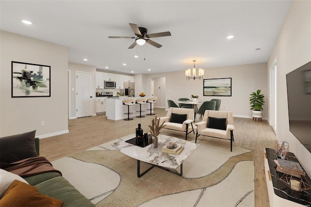 living room with light hardwood / wood-style flooring and ceiling fan with notable chandelier