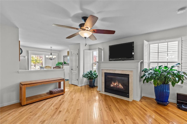 living room with ceiling fan with notable chandelier and light hardwood / wood-style floors