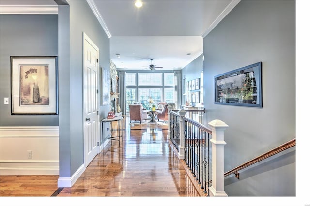 hallway featuring crown molding, baseboards, wood finished floors, and an upstairs landing