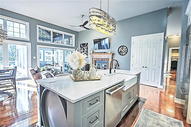 kitchen featuring pendant lighting, light countertops, a brick fireplace, open floor plan, and an island with sink