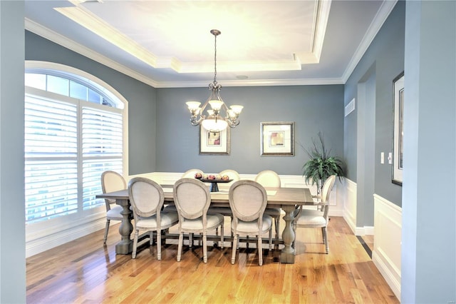 dining area featuring light wood finished floors, plenty of natural light, a raised ceiling, and a notable chandelier