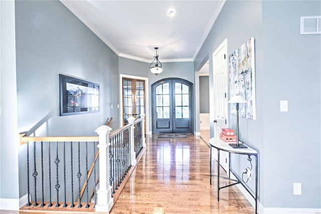 foyer entrance with baseboards, visible vents, ornamental molding, wood finished floors, and french doors