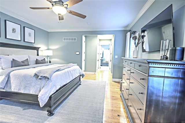 bedroom featuring light wood-style floors, baseboards, visible vents, and crown molding