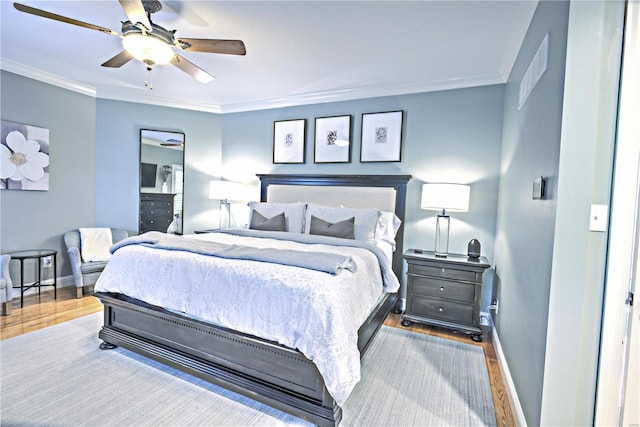 bedroom featuring a ceiling fan, crown molding, baseboards, and wood finished floors