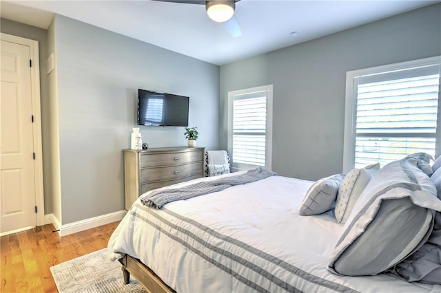 bedroom with light wood-type flooring, baseboards, and a ceiling fan