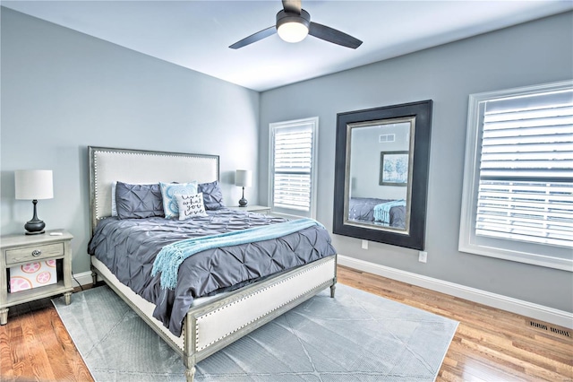 bedroom with light wood finished floors, baseboards, visible vents, and a ceiling fan