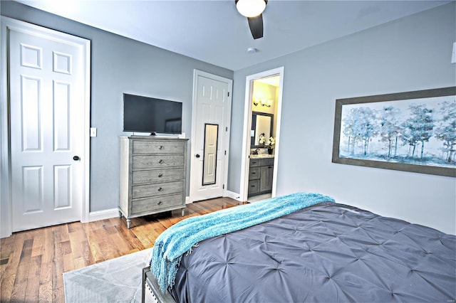 bedroom with ceiling fan, connected bathroom, baseboards, and wood finished floors