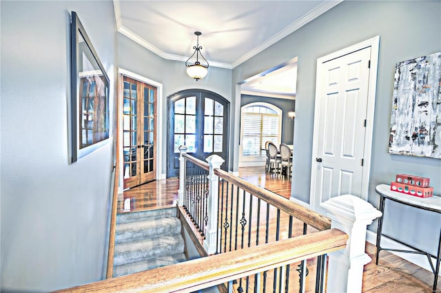 hall with baseboards, french doors, ornamental molding, wood finished floors, and an upstairs landing