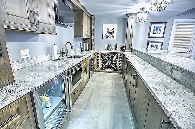 bar with beverage cooler, stainless steel microwave, pendant lighting, and a sink