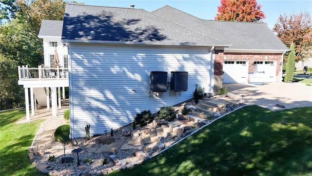 view of side of property featuring a shingled roof, brick siding, a yard, and a balcony