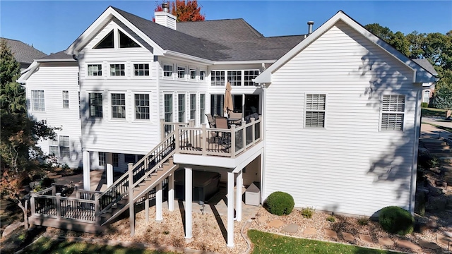 back of property featuring roof with shingles, stairs, a chimney, and a wooden deck