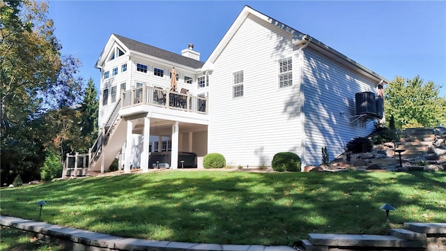 rear view of property featuring stairway, a lawn, and a chimney