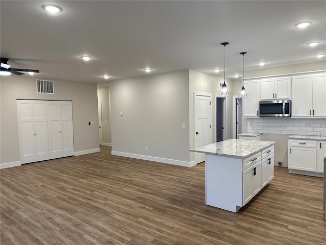 kitchen with decorative light fixtures, a kitchen island, white cabinetry, and tasteful backsplash