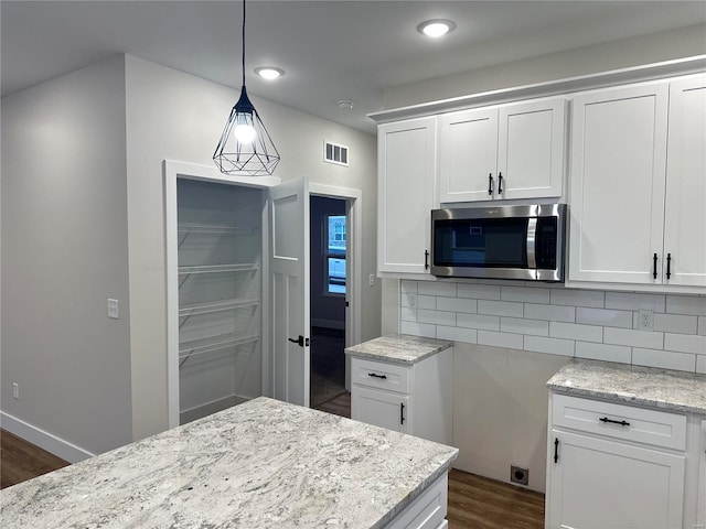 kitchen featuring light stone countertops, decorative backsplash, white cabinetry, and hanging light fixtures