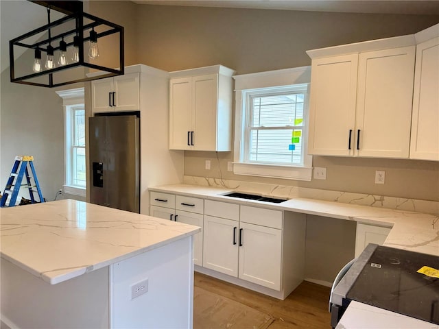 kitchen with stainless steel fridge, white cabinetry, electric range, light stone countertops, and decorative light fixtures