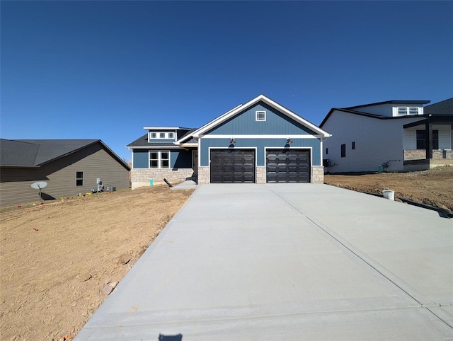 craftsman-style home with a garage, stone siding, and concrete driveway