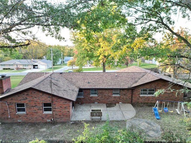 back of property featuring a playground and a patio