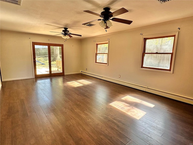 empty room featuring a wealth of natural light, dark hardwood / wood-style flooring, ceiling fan, and a baseboard heating unit