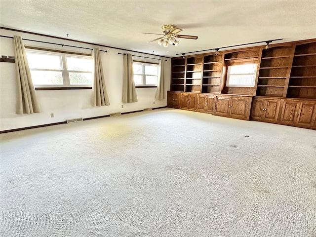 unfurnished living room featuring carpet, a textured ceiling, built in features, and ceiling fan