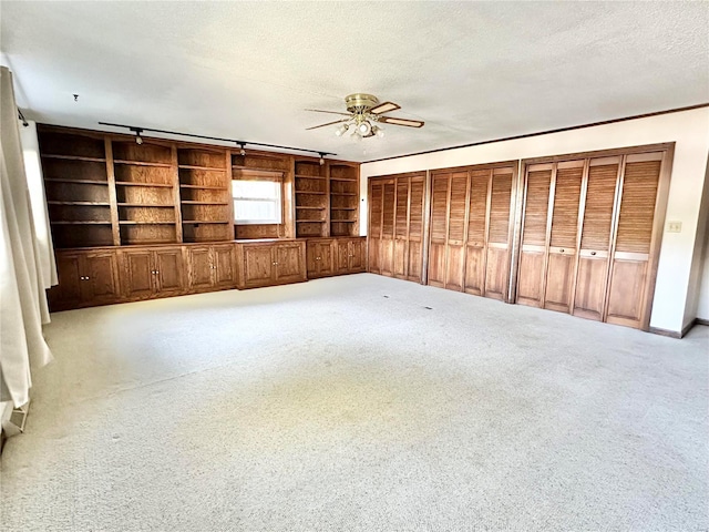 interior space featuring built in shelves, light colored carpet, and a textured ceiling