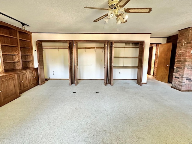 unfurnished living room featuring ceiling fan, light colored carpet, and a textured ceiling