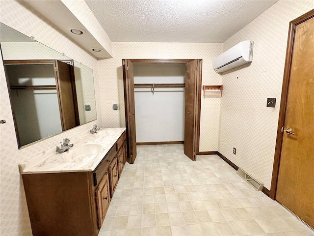 bathroom with an AC wall unit, vanity, and a textured ceiling