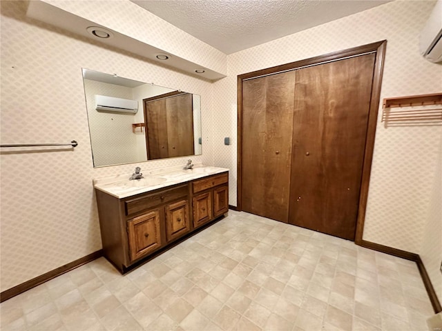 bathroom with vanity, an AC wall unit, and a textured ceiling