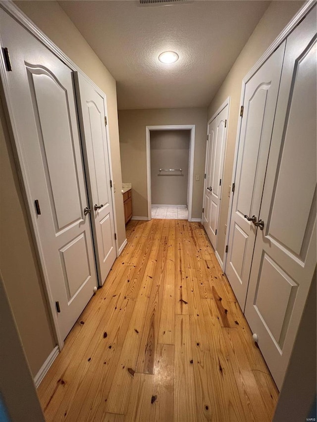 hall featuring light hardwood / wood-style floors and a textured ceiling